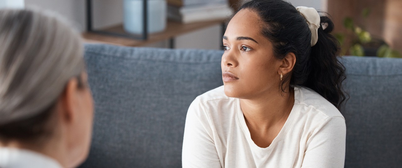 Young woman sitting on a couch, listening attentively during a conversation.